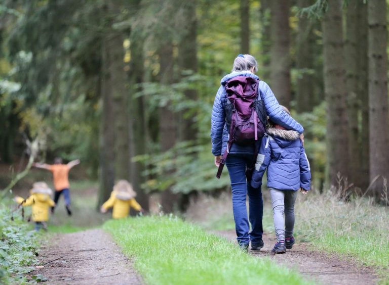 A family walking through the woods in autumn winter time