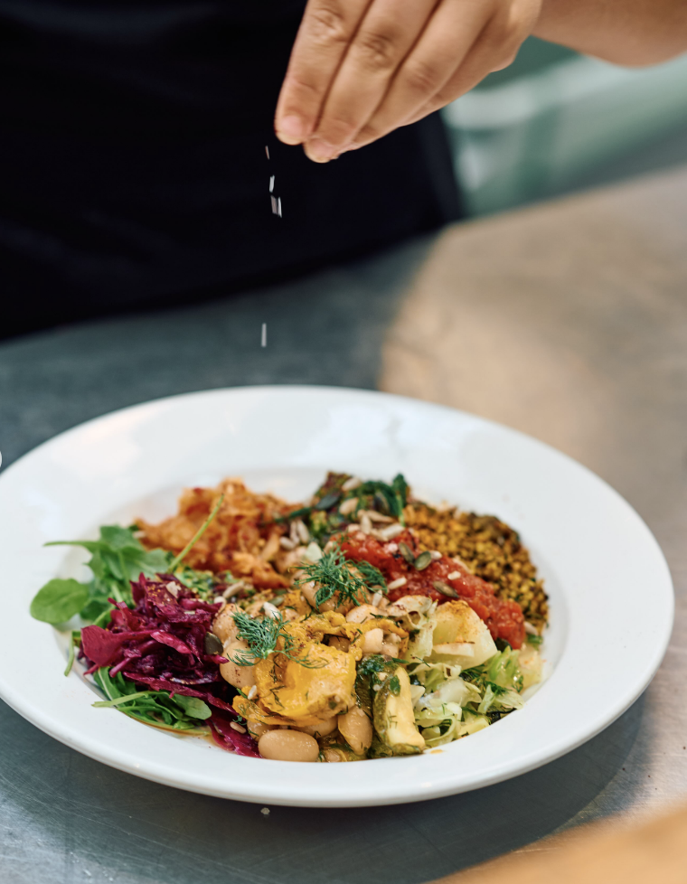 One of the healthy vegetarian dishes at Popup cafe in Deal being seasoned atop a stainless steel kitchen worktop.